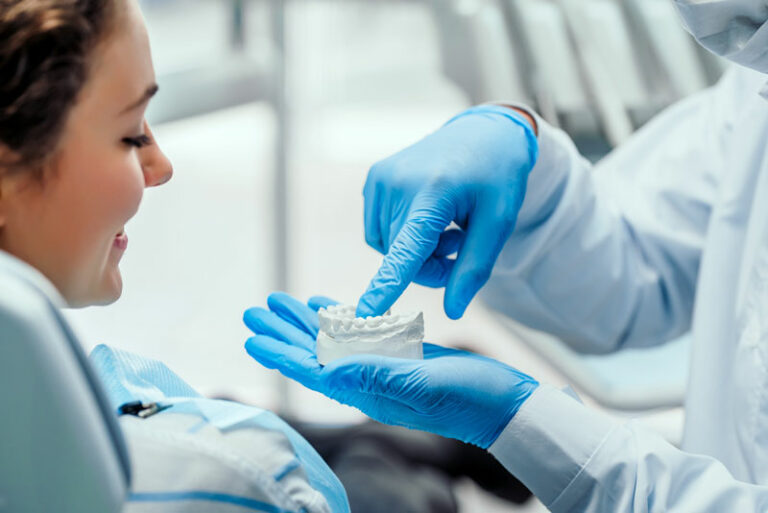 dentist-showing-an-implant-patient-a-dental-implant-model